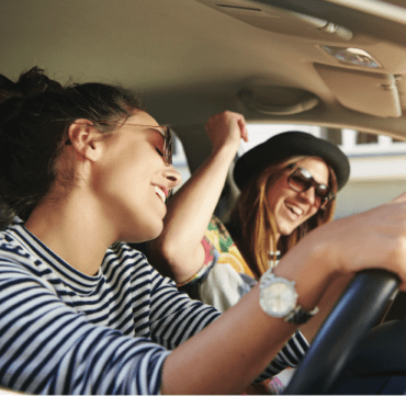 Two women dancing to music in the car