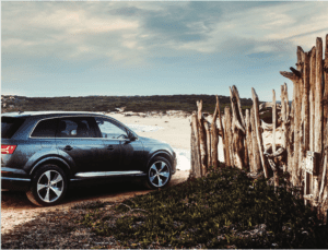 Car driving onto beach carefully through wooden fence