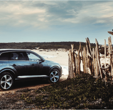 Car driving onto beach carefully through wooden fence